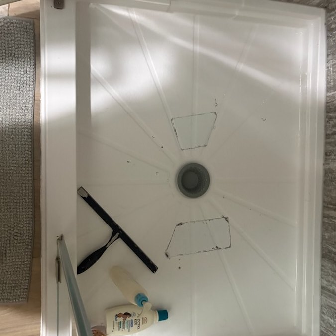 Before — a second view of the cracked shower pan floor and its broken-through holes.