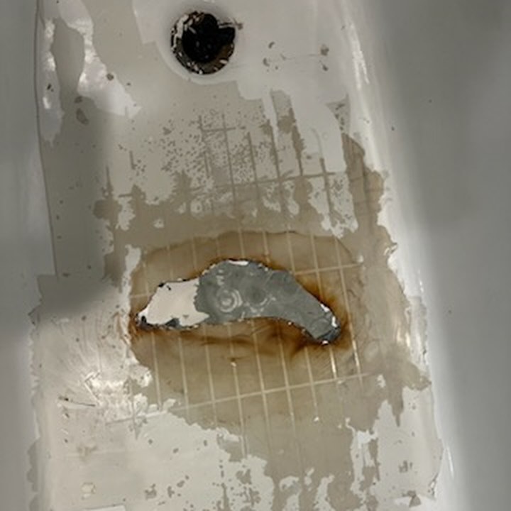 Before — a stripped tub floor with a rusted, previously patched crack running across the foot area.
